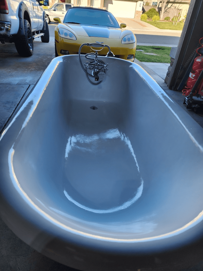 Bathtub in garage with yellow car outside.