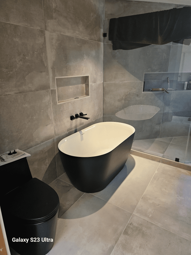 Modern bathroom with black bathtub and toilet.