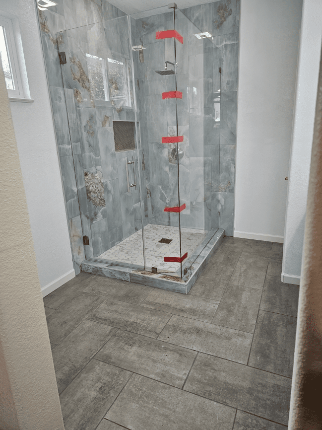 Glass shower with gray tile walls and floor.